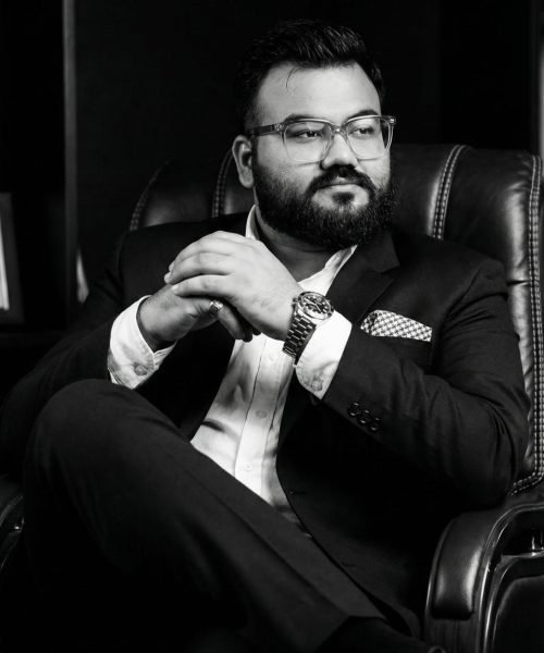 Ali Hassan in suit sitting confidently.